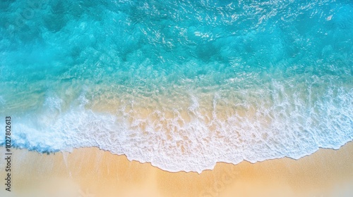 Drone shot of a sunny coastal scene featuring turquoise water, gentle waves, and a stretch of golden sand