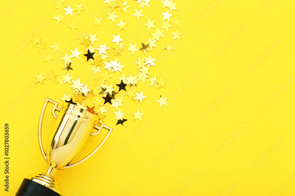 Golden trophy cup with confetti on yellow background