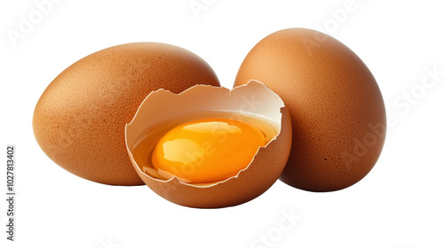 Fresh brown eggs with one cracked open revealing a bright yellow yolk on a wh...