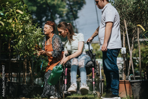 An elderly woman, a girl in a wheelchair, and a boy with Down syndrome enjoy gardening together. The image captures community, diversity, and inclusion in an outdoor setting. photo