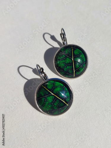 Handmade resin earrings real green leaves encased in a transparent finish close up white background. Leverback hooks, secure wear, nature-inspired jewelry collection, handcrafted jewellery, accessory photo