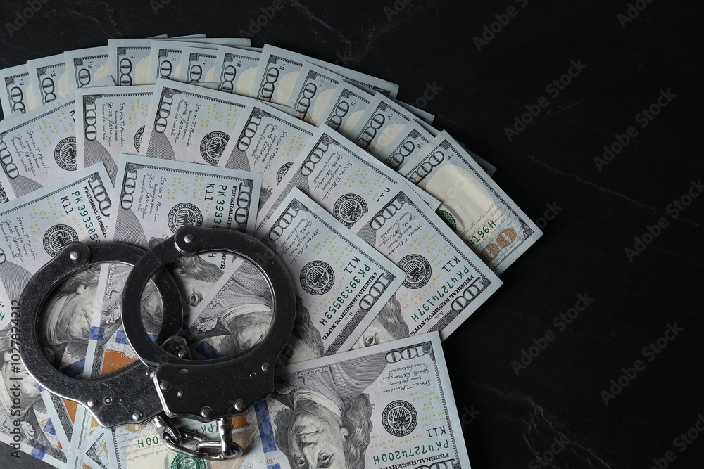 Corruption. Handcuffs and dollar banknotes on black table, top view Corruption. Handcuffs and dollar banknotes on black table, top view