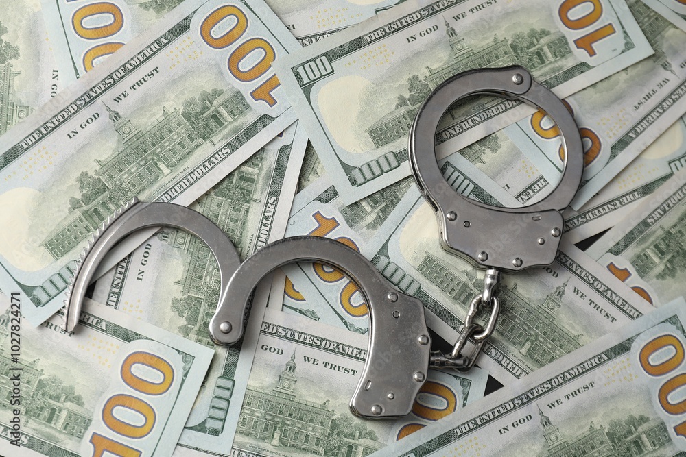 Corruption. Handcuffs on dollar banknotes, flat lay Corruption. Handcuffs on dollar banknotes, flat lay