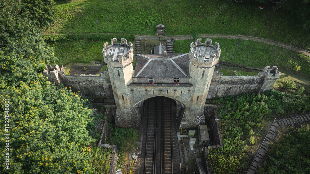 Rail track tunnel with castle looking house on top, in a green hill, East Sussex, UK
