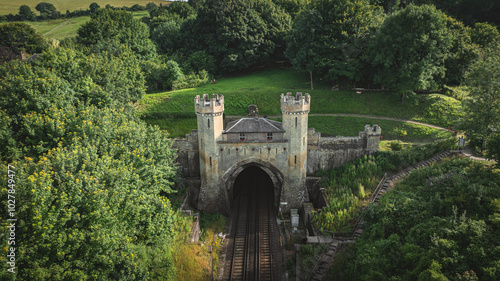 Rail track tunnel with castle looking house on top, in a green hill, East Sussex, UK