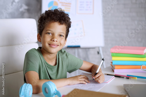 Bilde på lerret Close up portrait of adorable African American schoolboy sitting at the table wi
