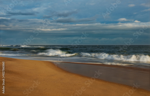 Beach in Sri Lanka (Ceylon) with the waves and sandy coast, sunset or sunrise landscape with beautiful dramatic sky. Blue Indian ocean photo