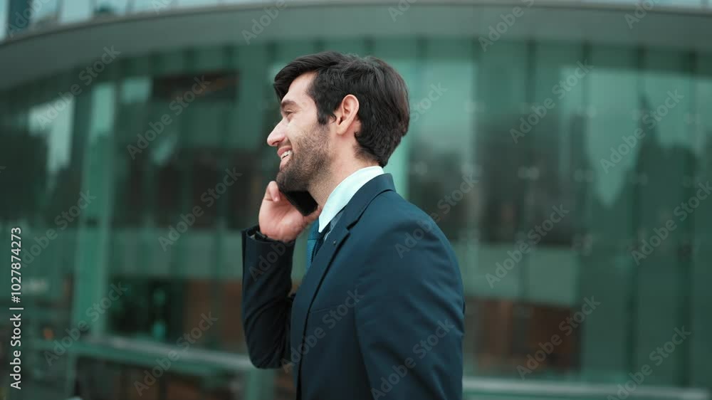 Skilled caucasian project manager calling phone while walking at city with blurred background. Skilled businessman using smart phone talking to project manager with blurred background. Exultant. Skilled caucasian project manager calling phone while walking at city with blurred background. Skilled businessman using smart phone talking to project manager with blurred background. Exultant.