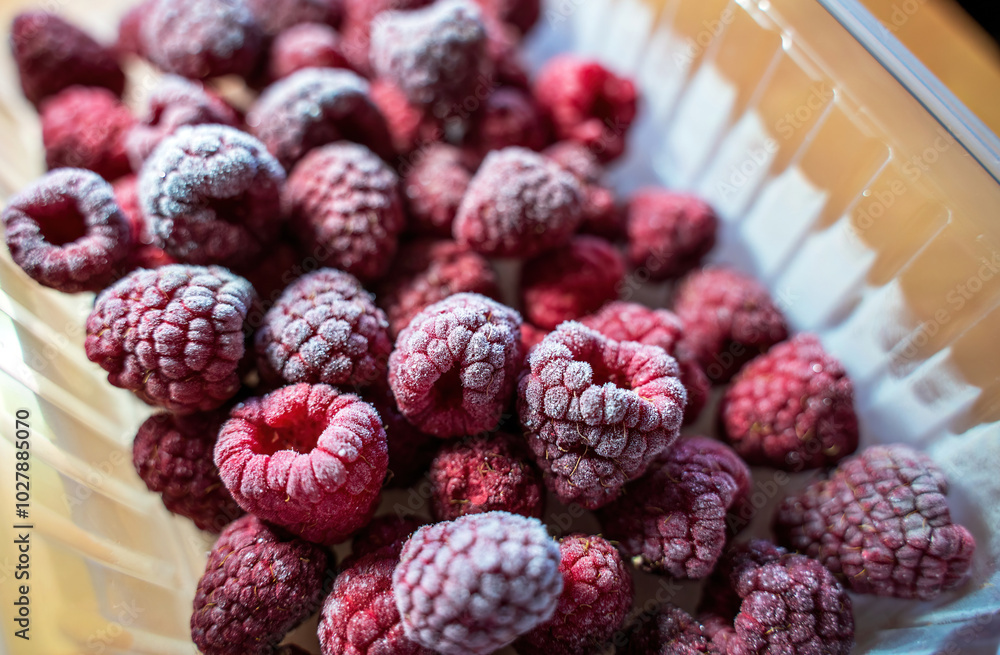 A vibrant close-up image of frozen raspberries, showcasing their bright red color and frosted texture. Perfect for concepts related to freshness, natural food & healthy eating. Berries selective focus