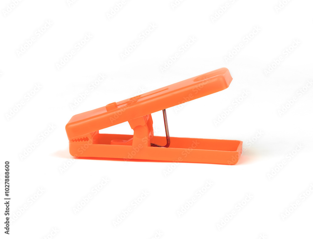 Bright orange clothespin on a white surface Bright orange clothespin on a white surface