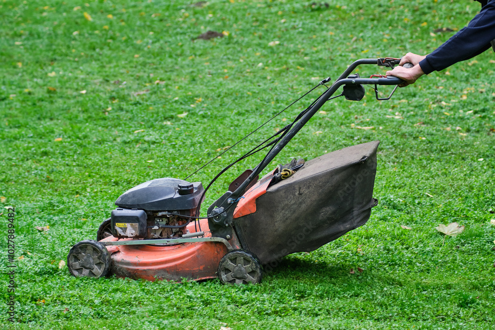 Faceless Person Mowing Grass with a Lawn Mower Faceless Person Mowing Grass with a Lawn Mower