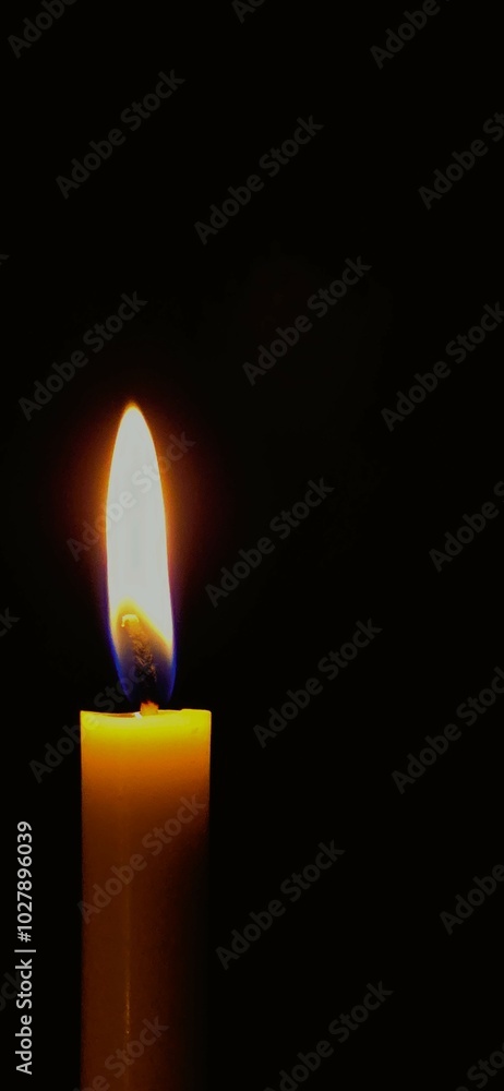 A close-up photograph of a single candle flame against a pitch-black background. A close-up photograph of a single candle flame against a pitch-black background.