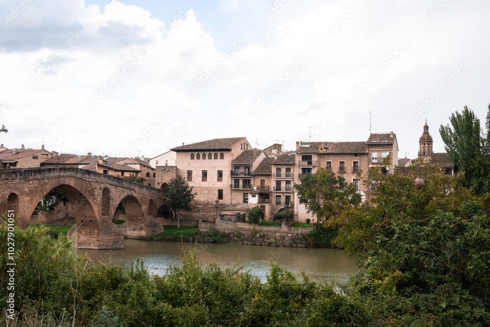 a river runs through a town with buildings and trees .Puente La Reina, Navarra, Spain a river runs through a town with buildings and trees .Puente La Reina, Navarra, Spain