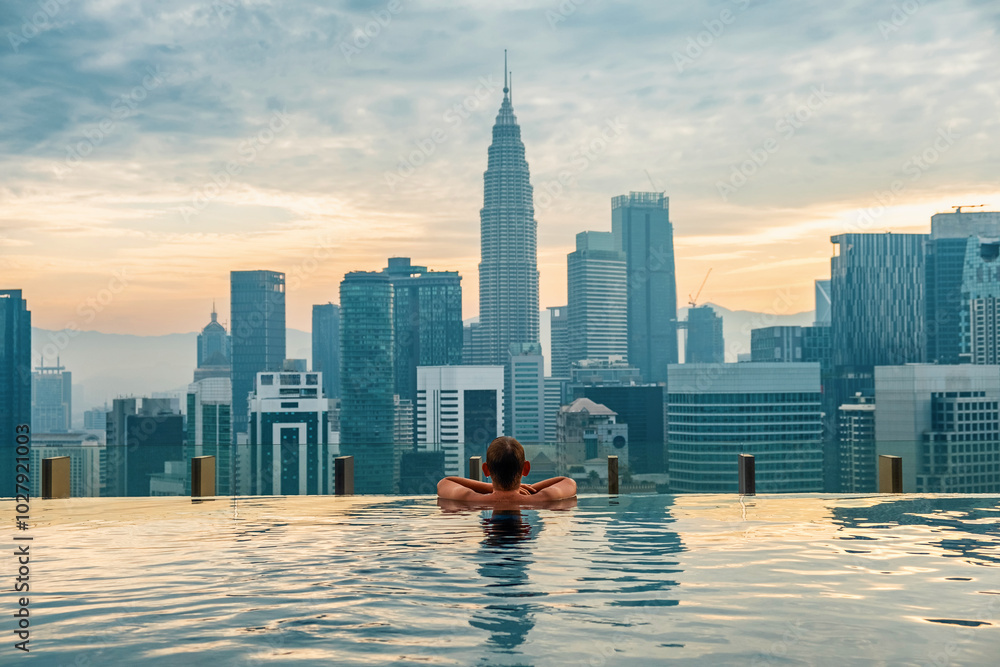 Φωτογραφία Man tourist relaxing in infinity roof top swimming pool at sunrise, Kuala Lumpur, Malaysia