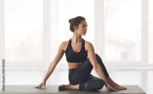 Cow Face Pose. Attractive Girl Practicing Yoga At Studio, Sitting In Gomukasana Position, Looking At Free Space photo