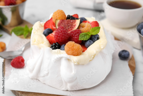 Pavlova cake (meringue dessert) with whipped cream, fresh berries, fig and mint on table, closeup photo