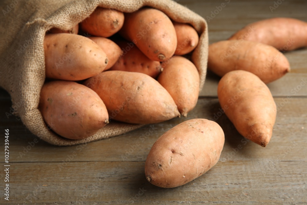 Sack with fresh raw sweet potatoes on wooden table, closeup Sack with fresh raw sweet potatoes on wooden table, closeup