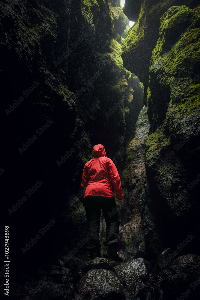 Hiker in a red jacket exploring Rauðfeldsgjá Gorge, a mossy canyon on Snaefellsnes Peninsula, Iceland. Hiker in a red jacket exploring Rauðfeldsgjá Gorge, a mossy canyon on Snaefellsnes Peninsula, Iceland.