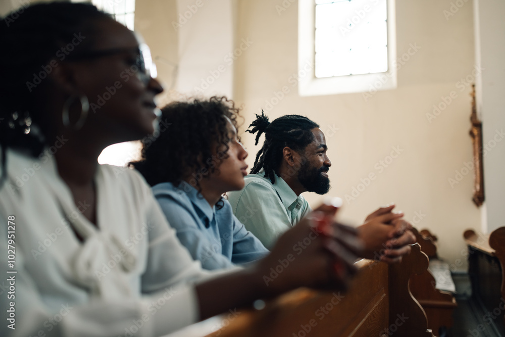 Family praying together in church pew holding hands Family praying together in church pew holding hands