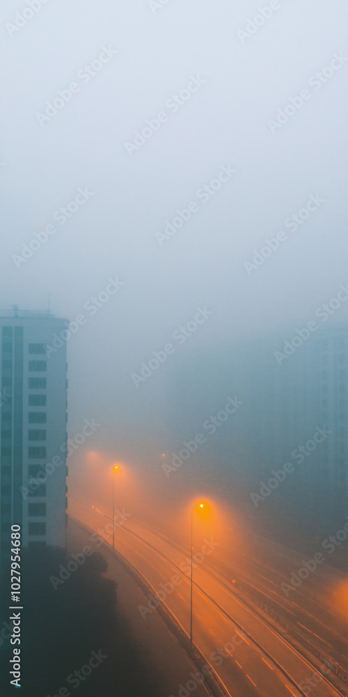 Obraz premium Misty night scene with high-rise buildings illuminated by streetlights, creating a captivating and atmospheric urban landscape, perfect for minimalist mobile phone wallpapers