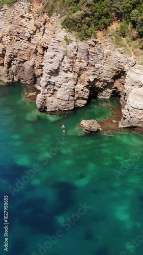 Aerial view of vacationers jump into the sea