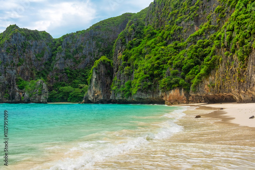 Maya Bay tropical sandy beach with turquoise water in lagoon on sunny day on Phi Phi islands, Krabi, Thailand with nobody. Empty beach with cliff rocks and lush greenery. Travel and tourism in Asia