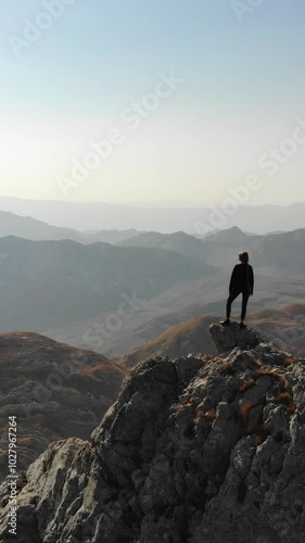 Strong independent woman standing on a mountain ridge.