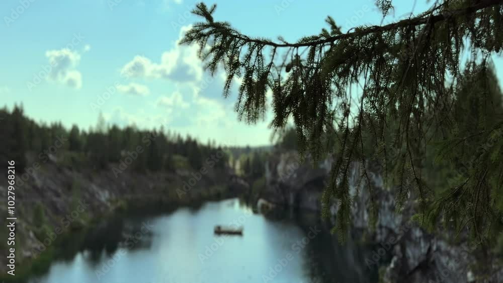 A pine branch sways gently against the backdrop of a serene blue lake and rocky shores. The peaceful scenery highlights the natural beauty of the landscape, blending water, stone, and greenery. High A pine branch sways gently against the backdrop of a serene blue lake and rocky shores. The peaceful scenery highlights the natural beauty of the landscape, blending water, stone, and greenery. High