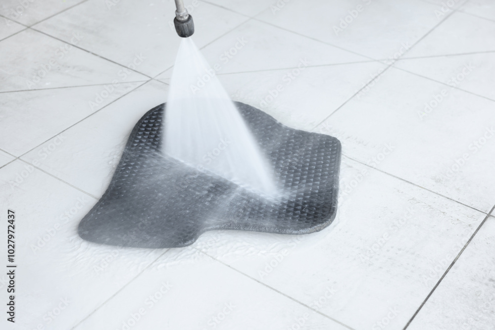 Washing rubber car mat with high pressure water jet indoors, closeup Washing rubber car mat with high pressure water jet indoors, closeup