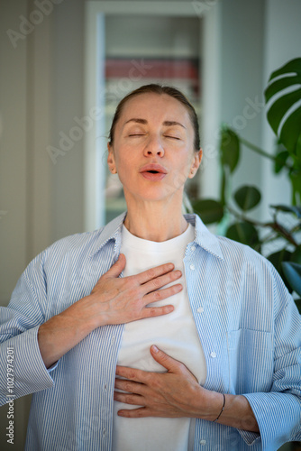 Cuadro en lienzo Calm middle aged woman practicing breathing meditation techniques standing with closed eyes, self caring at home