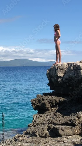 Girl with a perfect figure stands on the empty rocky shore