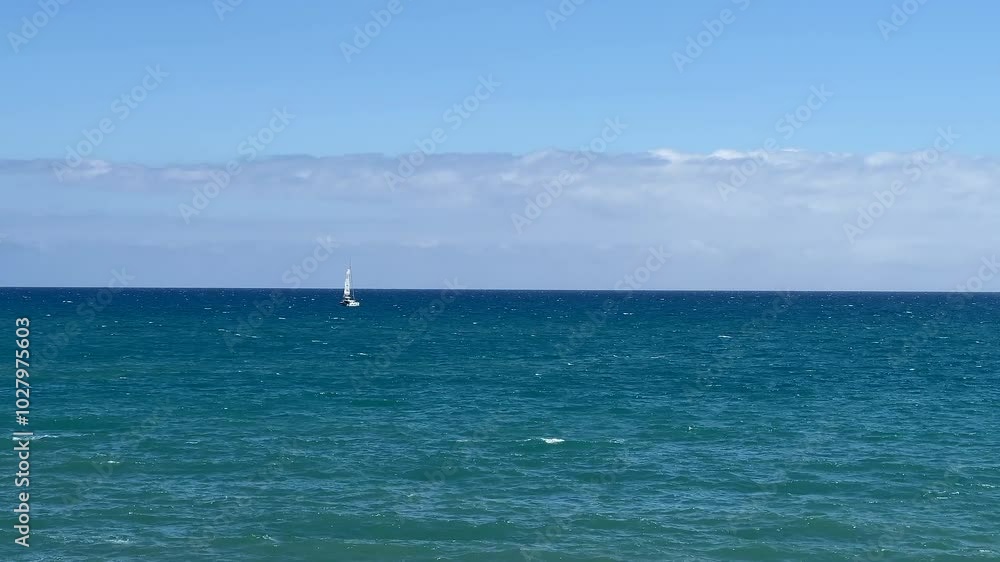 A lone sailboat navigates the expansive ocean under a clear blue sky, symbolizing solitude and adventure, ideal for summer and coastal retreats A lone sailboat navigates the expansive ocean under a clear blue sky, symbolizing solitude and adventure, ideal for summer and coastal retreats