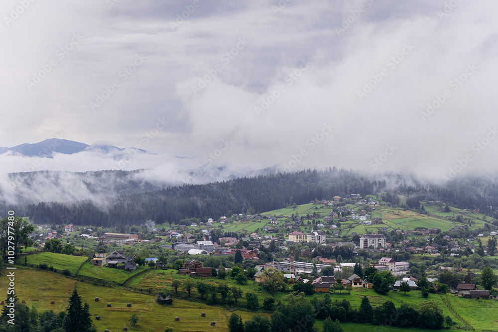 Fototapeta premium Misty morning in Vorokhta village with scenic view of Carpathian hills and fog-covered mountains