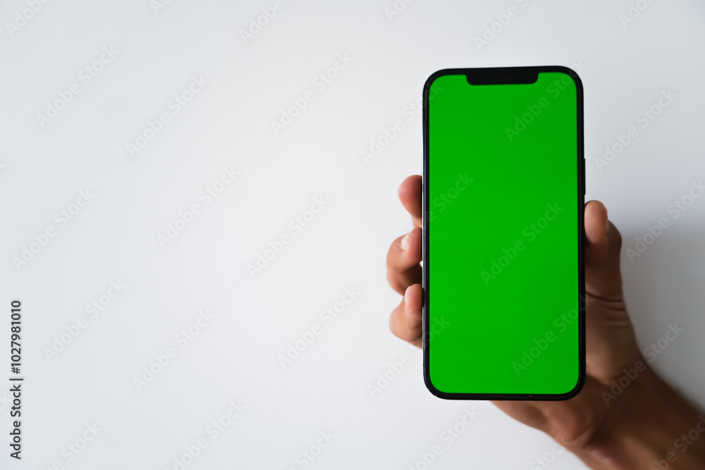 A close-up of a hand holding a smartphone with a green screen, ideal for mockups or design insertions A close-up of a hand holding a smartphone with a green screen, ideal for mockups or design insertions