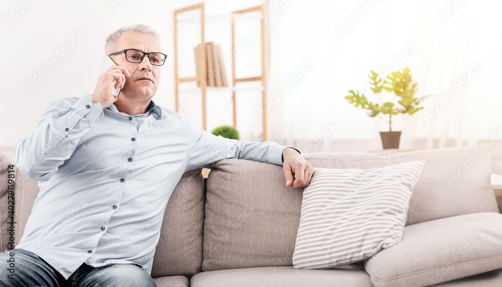 Business Calls Concept. Concerned Senior Man Talking On Mobile Phone Sitting On Sofa, Empty Space Business Calls Concept. Concerned Senior Man Talking On Mobile Phone Sitting On Sofa, Empty Space