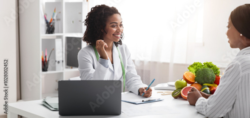 Friendly nutritionist african woman giving consultation to patient in her clinic, nutrition and diet concept, copy space