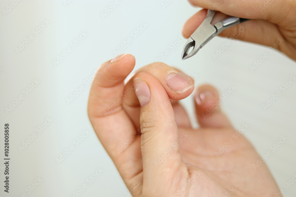 Close up of woman removing cuticles from fingers with tweezers, natural manicure Close up of woman removing cuticles from fingers with tweezers, natural manicure