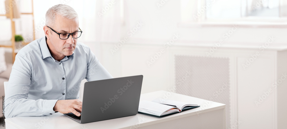 Mature Entrepreneur. Attentive Senior Man In Eyewear Using Computer Laptop Sitting At Desk, Free Space Mature Entrepreneur. Attentive Senior Man In Eyewear Using Computer Laptop Sitting At Desk, Free Space