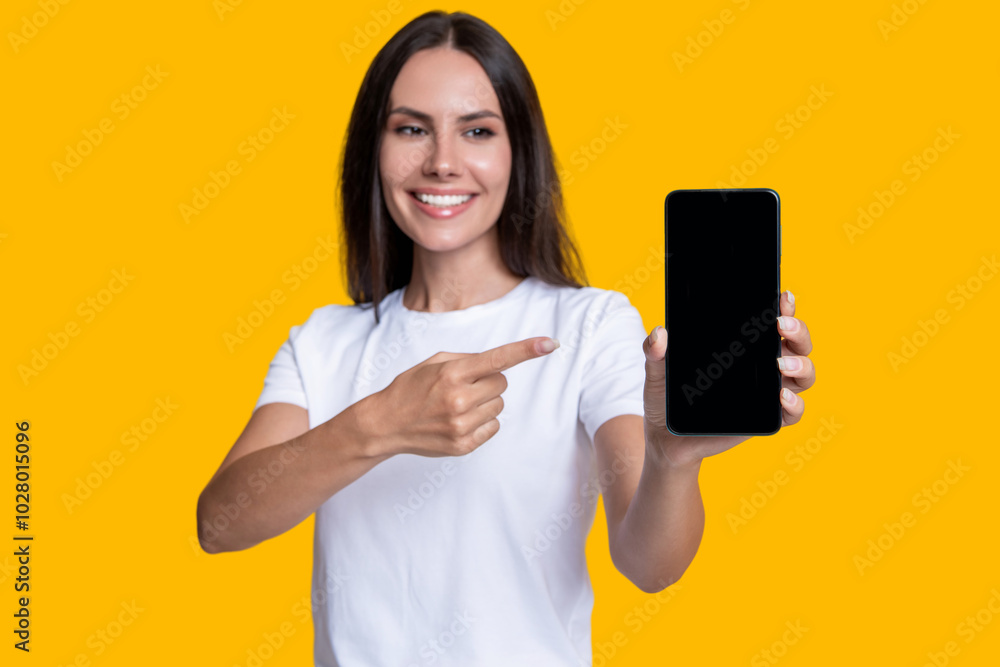 New phone app. Girl offer advertisement. Presenting product. Advertisement of business app. Woman presenting phone screen. Young girl showing phone isolated yellow. Millennial woman. Pointing finger New phone app. Girl offer advertisement. Presenting product. Advertisement of business app. Woman presenting phone screen. Young girl showing phone isolated yellow. Millennial woman. Pointing finger