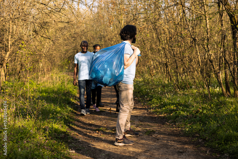 Fototapeta premium Satisfied diverse activists enjoying clean forest environment after finishing litter cleanup activity, community service. Group of volunteers successfully tidying the natural ecosystem.