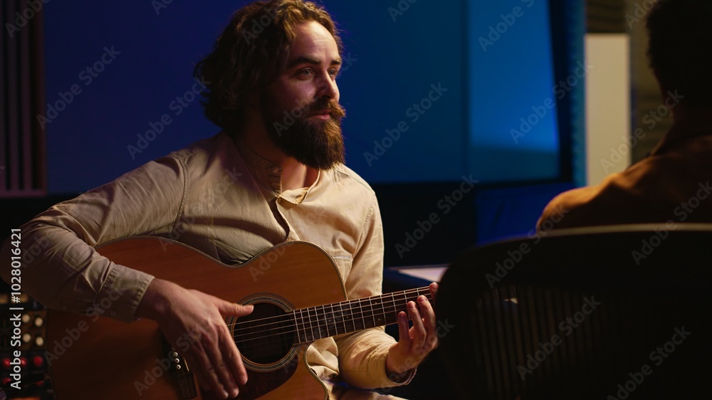 Obraz premium Skilled composer producing and recording new track on guitar, creating a live performance in control room. Songwriter artist composing music for his new album. Close up. Camera A.
