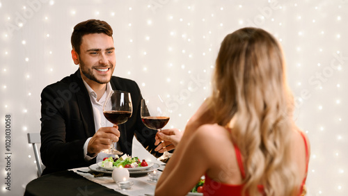 Toast For Us. Romantic couple clinking red wine glasses during Valentine Day dinner in restaurant. selective focus to man