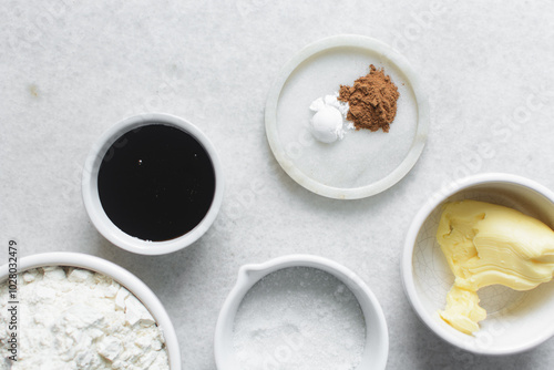 mise en place of ingredients for making molasses cookies, top view of sugar, butter, flour molasses on a marble table, process of making molasses spice cookies