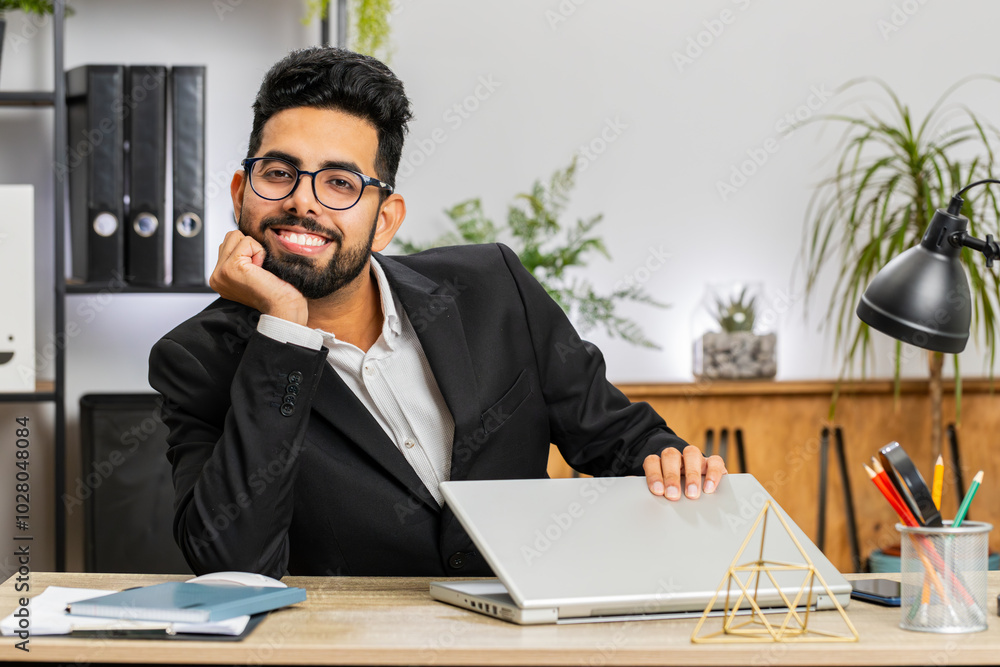 Portrait of Indian bearded businessman face freelancer at home office modern workplace working on laptop computer. Manager freelancer Arabian man works on notebook send messages makes online purchases Portrait of Indian bearded businessman face freelancer at home office modern workplace working on laptop computer. Manager freelancer Arabian man works on notebook send messages makes online purchases