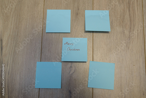 Merry Christmas written on sticky notes on a wooden background