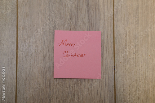 Merry Christmas written on sticky notes on a wooden background