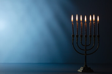Jewish holiday Hanukkah concept. Menorah with burning candles on dark blue background, space for text