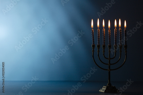 Jewish holiday Hanukkah concept. Menorah with burning candles on dark blue background, space for text photo