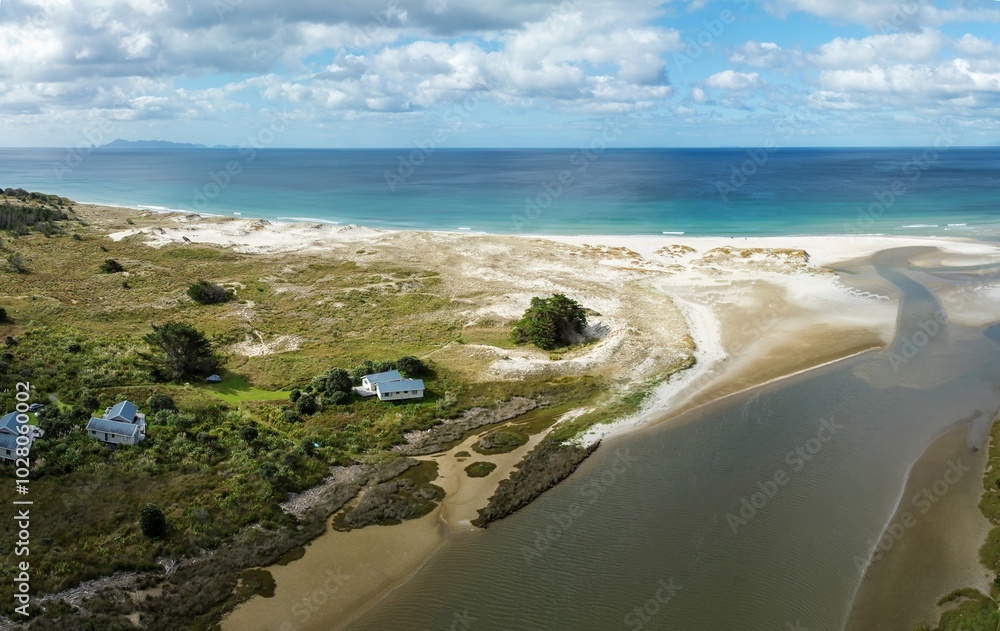 Holiday homes and the Pakiri River flowing into the ocean at Pakiri, Auckland, New Zealand.