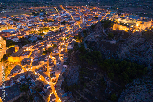 Aerial view of medieval fortified Castalla Castle on top of stone hill on background with townscape in twilight, province of Alicante, Spain.. photo